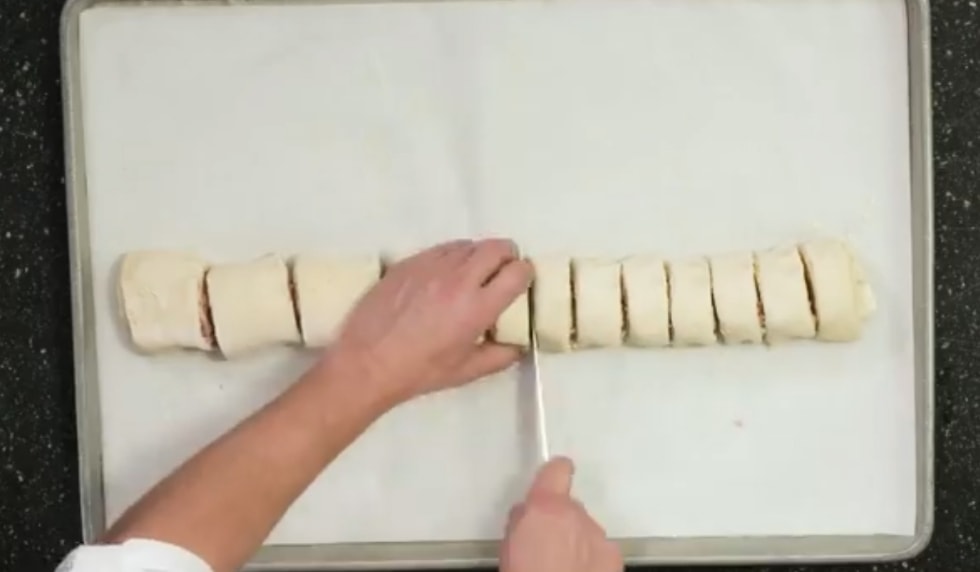 preview from video, an overhead photo showing a chef slicing pizza rolls