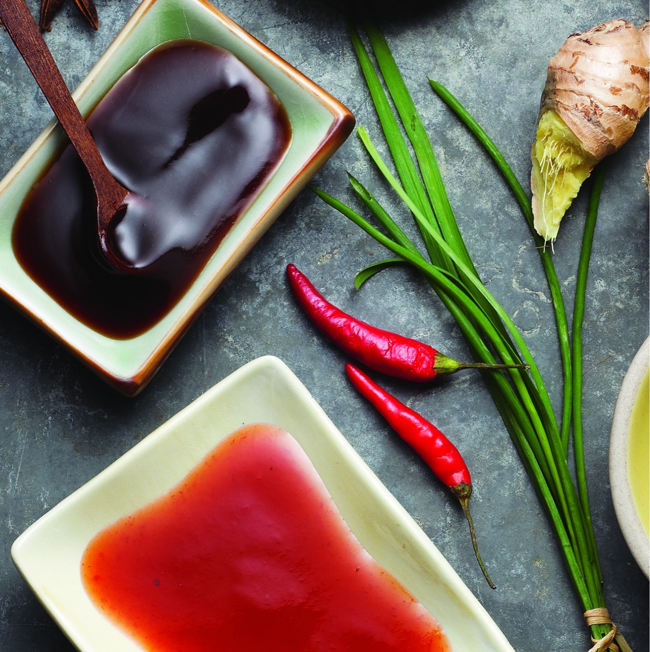 overhead photo of sauces in a bowl next to green onions and chili peppers