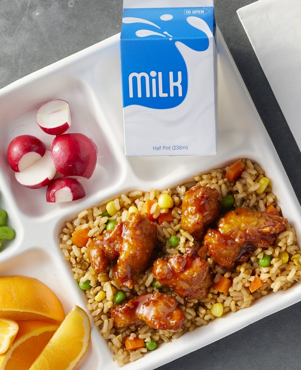 Stir fry on a school lunch tray with a carton of milk and raw radishes