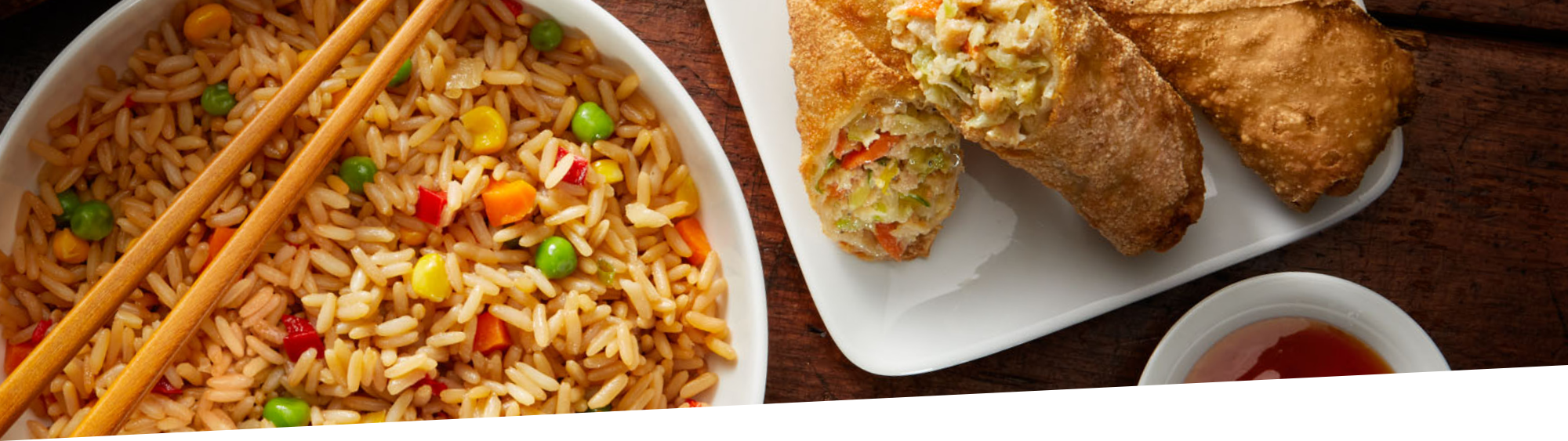 bowl of fried rice and a plate with some egg rolls