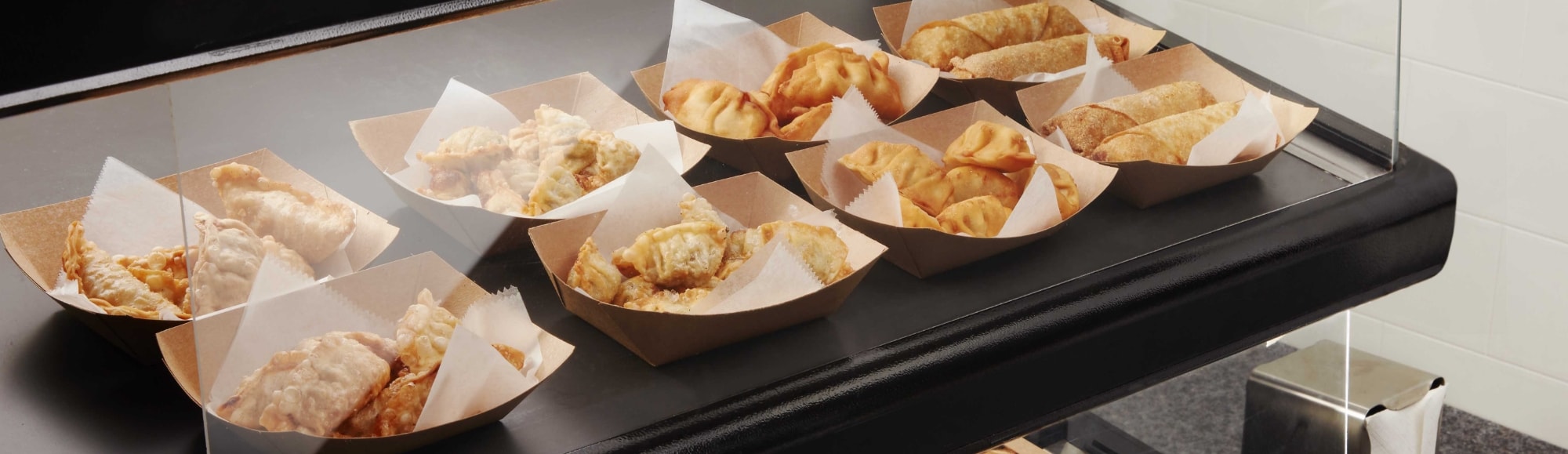 Dumplings in serving trays under a heating lamp