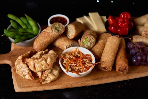 Chef One and Minh charcuterie board with egg rolls and dumplings
