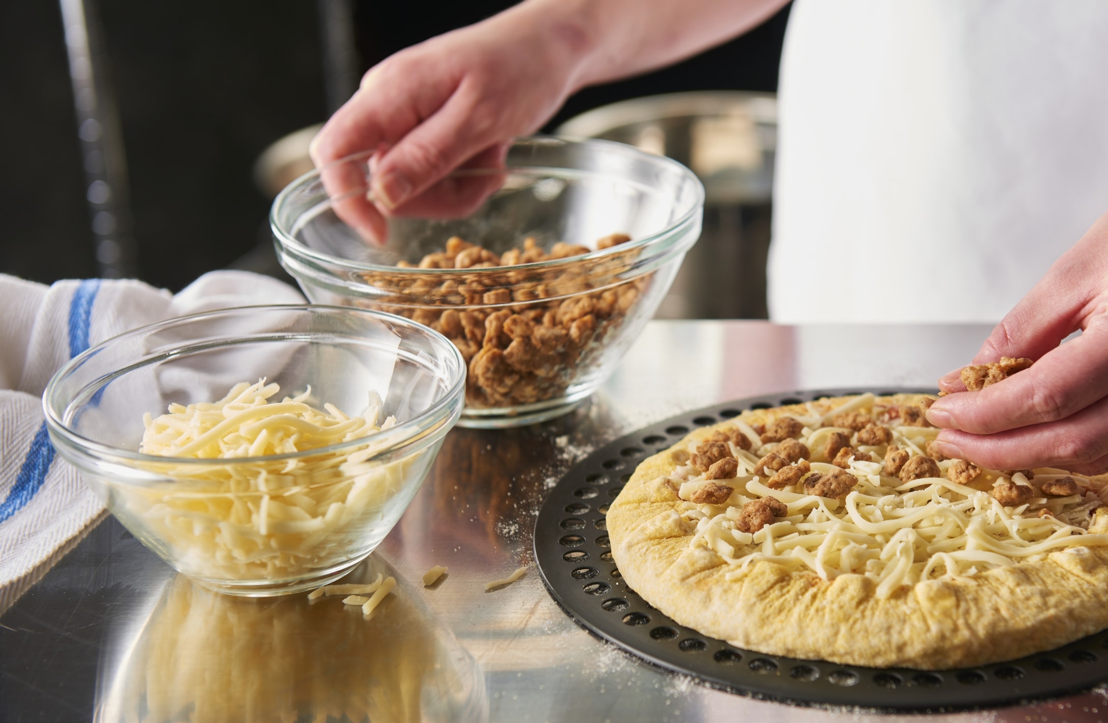 a chef topping scratch ready pizzas