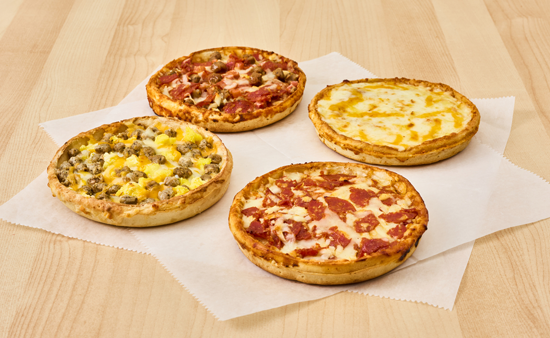 Four 5-inch Red Baron pizzas on deli paper on a wood counter top