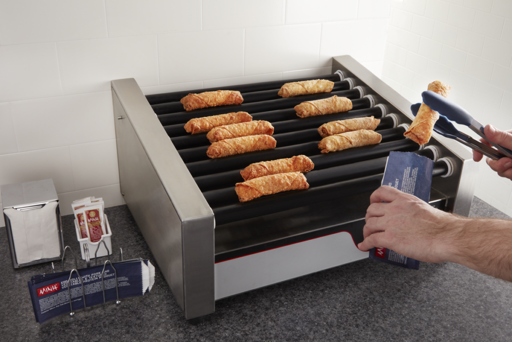 A customer reaching into a convenience store hot display case to grab a MINH® egg roll.